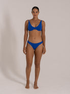 Front view of woman in a blue bikini set featuring a high-leg bottom cut