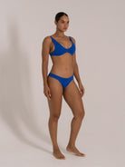 Side angle of model in a blue bikini set with stretch textured fabric