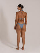 Woman wearing a blue gradient halter bikini with tie side bottom, back view, standing on neutral background.
