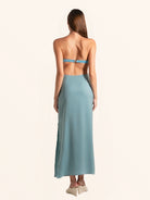 Rear side angle of blue green cut out maxi dress with flowing hemline