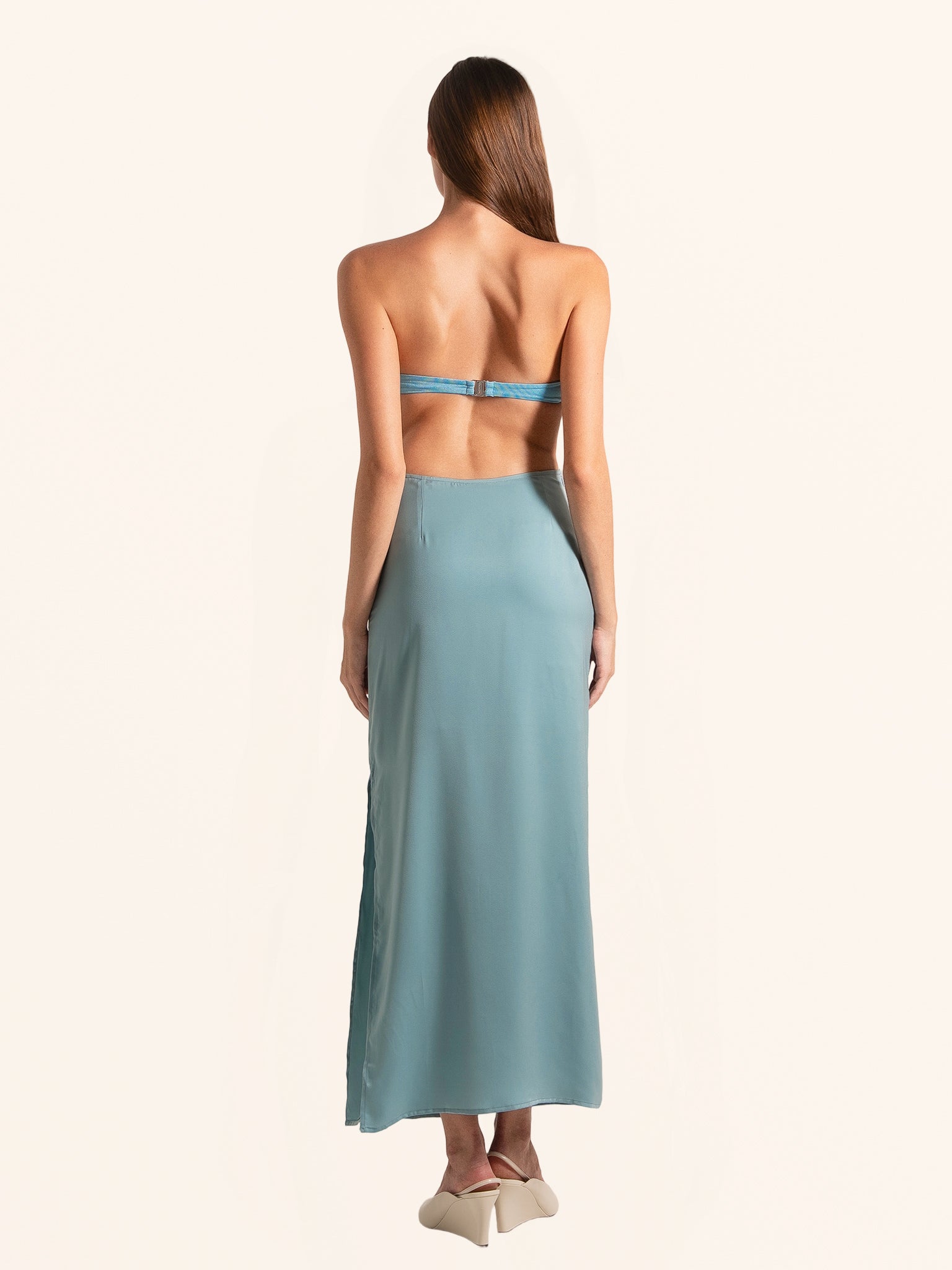 Rear side angle of blue green cut out maxi dress with flowing hemline