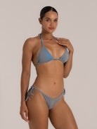 Model in a blue-grey string triangle bikini top looking sideways, showcasing minimalist design.