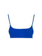 Bold blue jacquard square-neck bikini top against turquoise ocean waves, emphasizing summer color contrast.