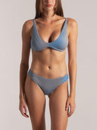 Woman in a shimmering blue metallic underwire bikini set, showcasing full front view of top and mid-rise bottom