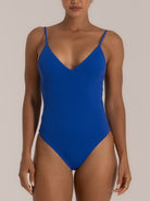 Front view of a woman wearing a blue one-piece swimsuit with thin spaghetti straps and a deep V neckline, offering a sleek and supportive fit.