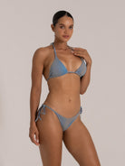 Close-up of a woman wearing a blue string bikini with a halter neck and ribbed texture.