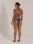 Model wearing blue textured triangle bikini set with halter neck top and tie side bottoms, view 1