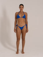 Model wearing blue textured triangle bikini set with halter neck top and tie side bottoms, view 3