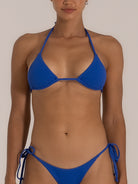 Front view of a woman in a royal blue textured triangle bikini set featuring halter neck ties and ruched side-tie bottoms, perfect for a classic yet vibrant swimwear style.