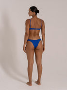 Back view of woman wearing a blue textured underwire bikini set with adjustable straps