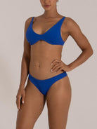 Close-up side profile of a woman in a blue underwire bikini set made from stretchy textured swimwear fabric.