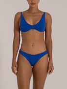 Front view of a woman wearing a textured blue underwire bikini set with scoop neckline and classic bikini bottoms.