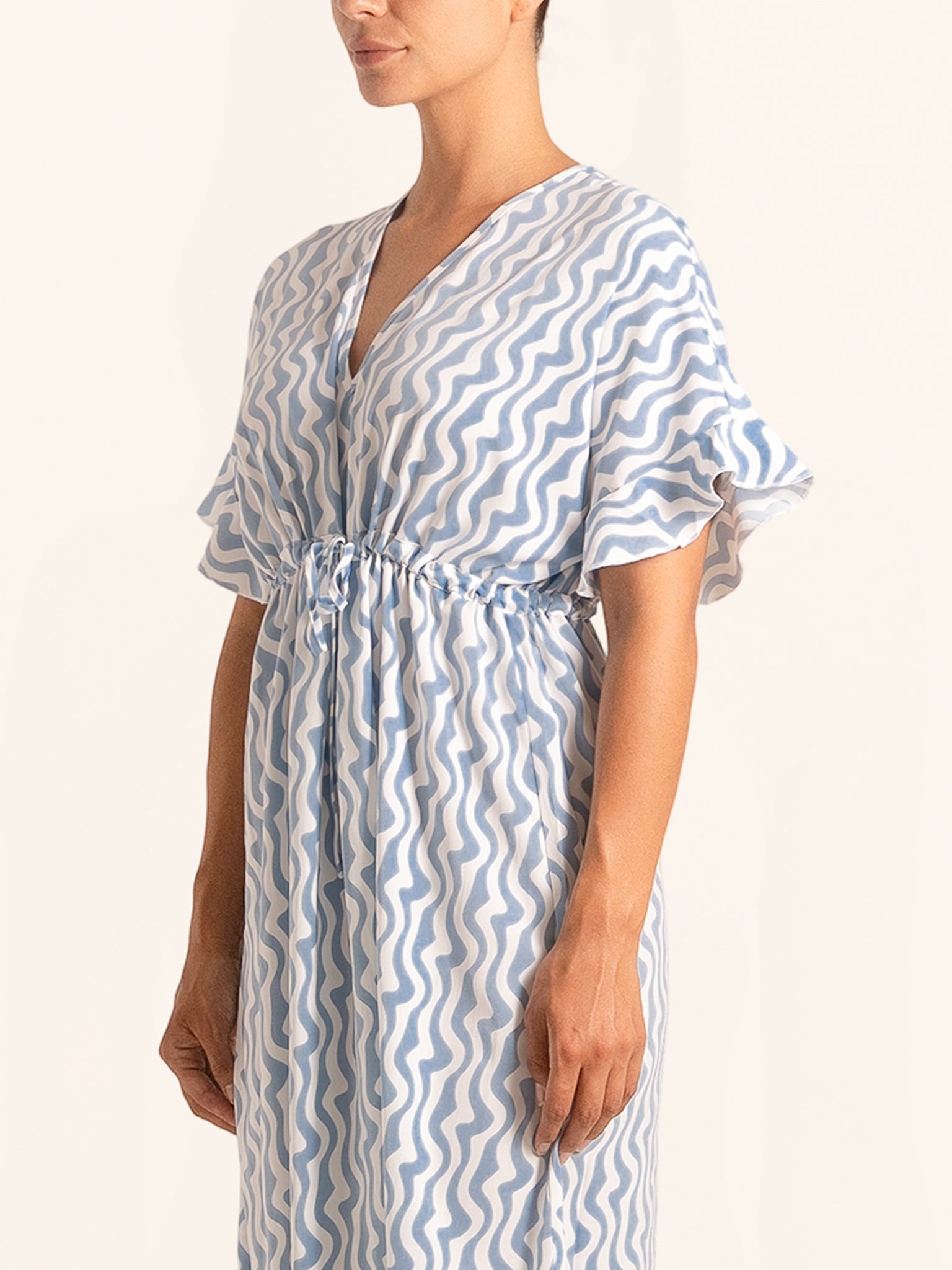 Closeup side angle of blue and white print dress with short flutter sleeves