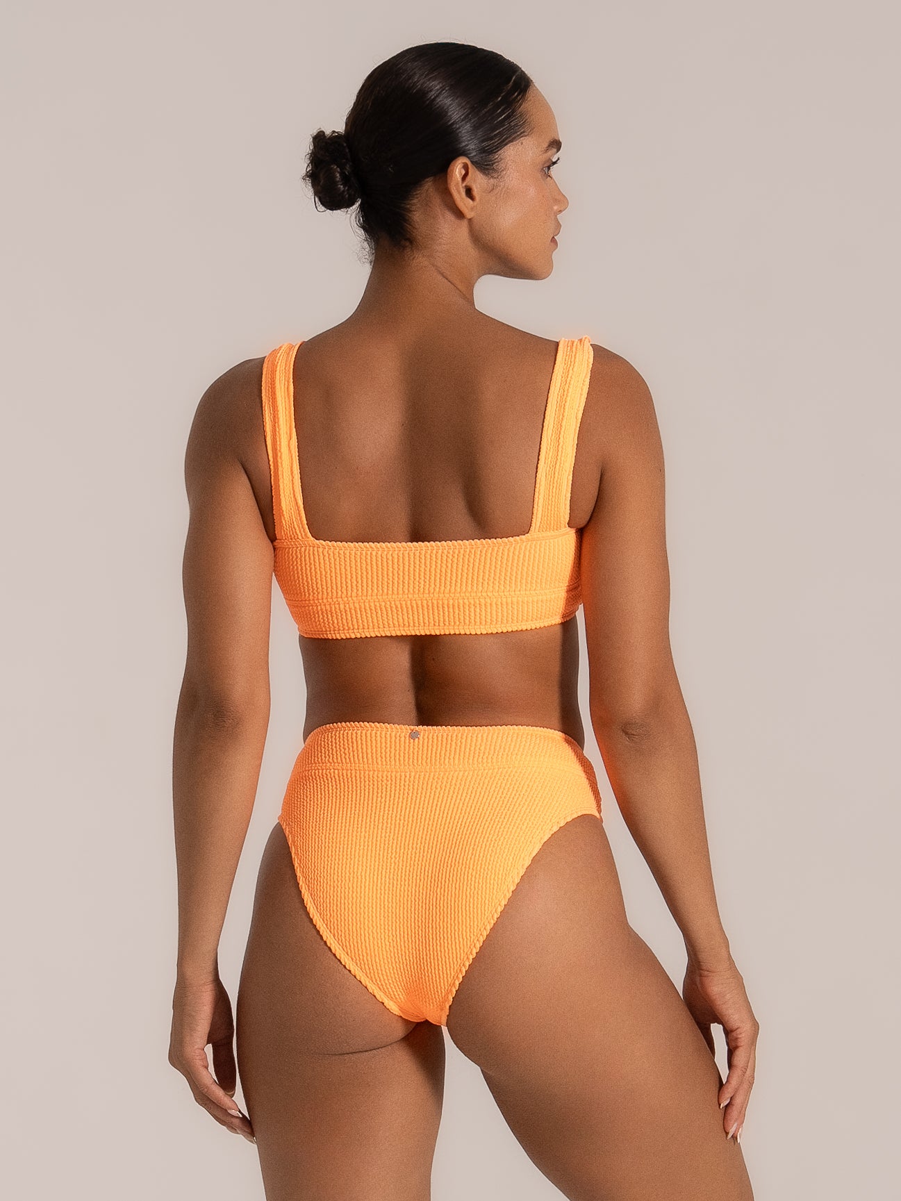 Back view of a bright orange textured bikini top with wide shoulder straps