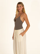 Side profile of a woman modeling a sleek charcoal gray one-piece swimsuit with thin straps from Ocean Mystery.
