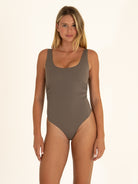 Front view of a woman wearing a charcoal gray scoop neck one-piece swimsuit with side ruching details.