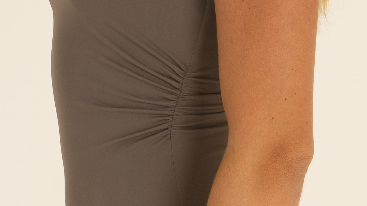 Close-up detail of the premium nylon fabric and elegant side ruching on the charcoal gray one-piece swimsuit.