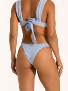 Back view of baby blue textured bikini bottom with cheeky thong cut and bow tie detail.