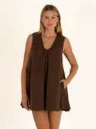 Woman modeling the ruched V-neck side of the chocolate brown reversible dress, demonstrating the clever functional dual-way pockets.