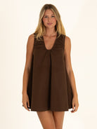 Front view of a woman wearing the chocolate brown reversible 100% cotton mini dress, showcasing the feminine ruched V-neckline.