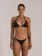 Woman posing in a chocolate triangle bikini set, facing forward with subtle smile.
