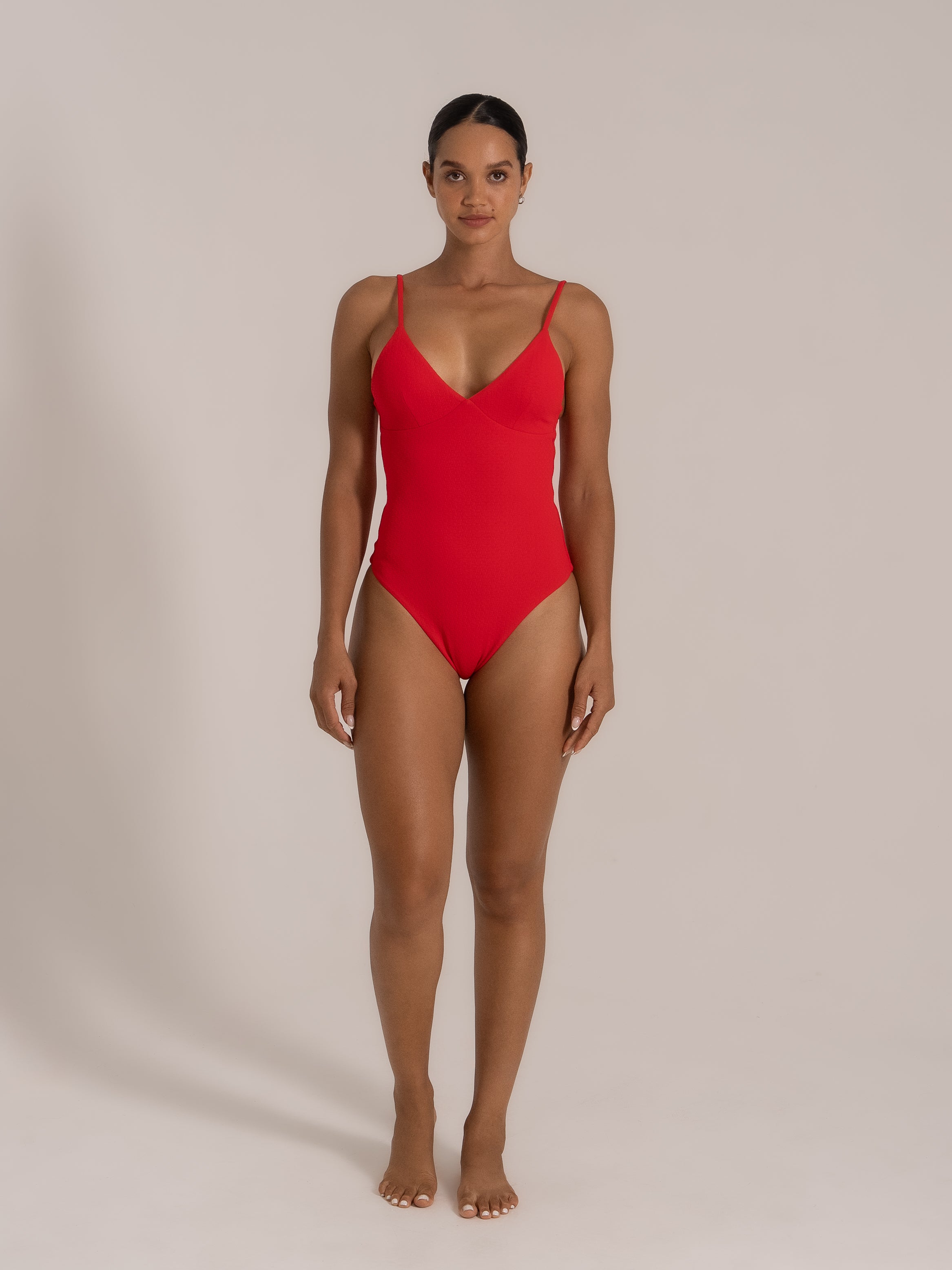 Front view of a red one-piece swimsuit with V-neckline and minimalist design.