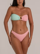 Front view of pastel colorblock bandeau bikini set in mint and pink with circular ring accents and textured design.