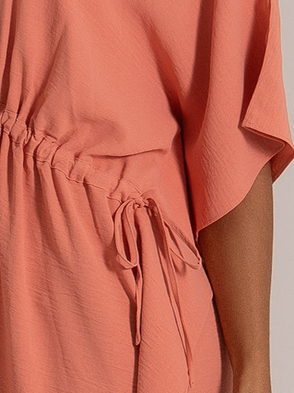 Close-up of coral dress side tie with adjustable drawstring at the waist for customizable fit