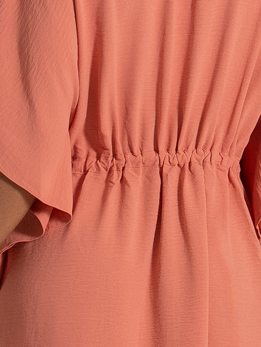 Back view of coral dress featuring elasticated waist with gathered stitching for a flattering silhouette