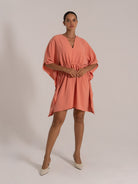 Front view of coral orange short dress with flowy sleeves and cinched waist
