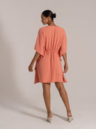Back view of coral orange V-neck mini dress with drawstring waist