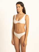 Front angled view of a model wearing the custom fit Ivory ribbed bikini set, featuring a scoop neck top and seamless-feel high-cut bottoms.