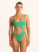 Front view of woman wearing green textured cut out one piece swimsuit with scoop neckline.
