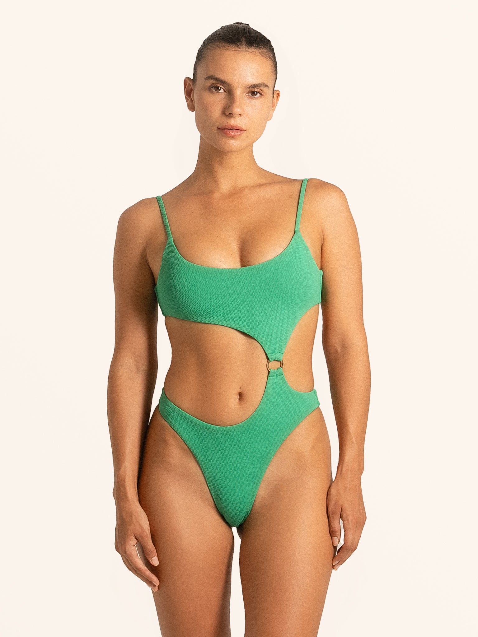 Front view of woman wearing green textured cut out one piece swimsuit with scoop neckline.