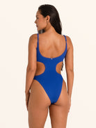 Side pose of woman in blue textured cut out one piece swimsuit with flattering fit.