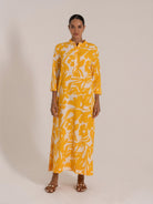 Woman wearing a yellow and white floral button-up maxi dress, front view