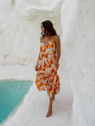 Woman wearing a floral print maxi dress with thin straps, enjoying the water view.