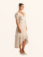 Side view of floral wrap dress with puff sleeves and asymmetrical hem