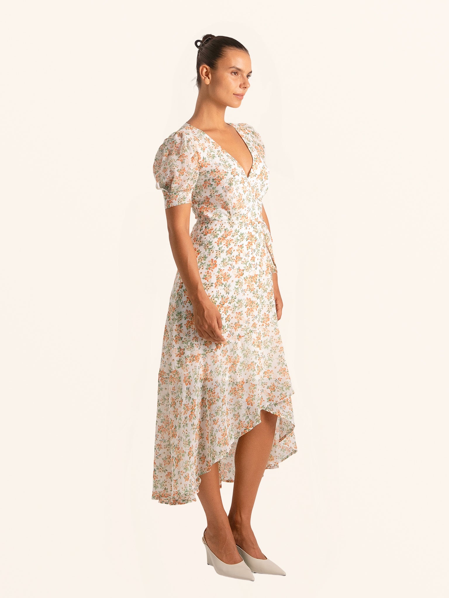 Side view of floral wrap dress with puff sleeves and asymmetrical hem