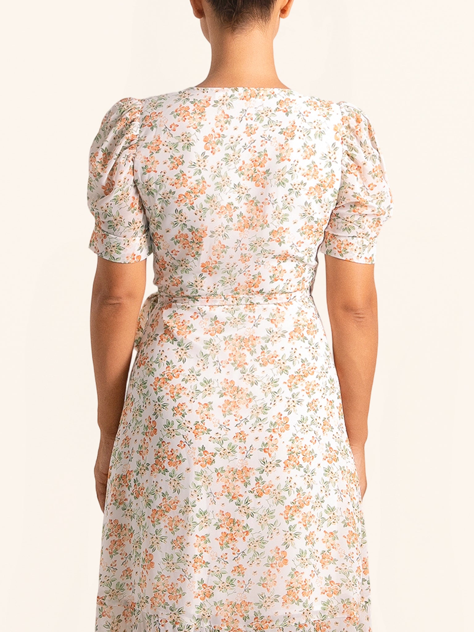 Back view of floral wrap dress with puff sleeves and tie waist
