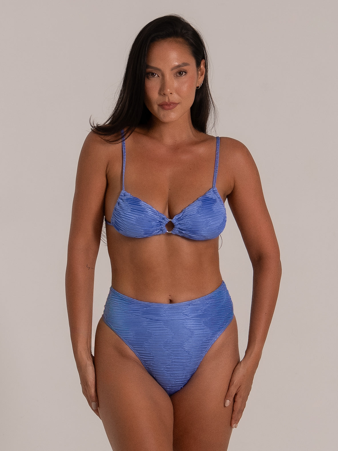 Full front view of model wearing ruched blue bikini top with center ring and high waist bottom