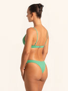 Over shoulder shot highlighting green bikini bottom in textured swim fabric.