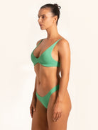 Three-quarter angle of green textured bikini bottom styled for modern beachwear.