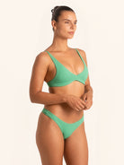 Three-quarter angle of green bikini top in a stylish swimwear look.