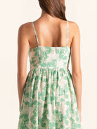 Back view of green floral spaghetti strap dress with fitted waist and flared hem