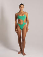 Front view of a green monokini swimsuit with scoop neck and side cutouts, styled for a flattering beach look.