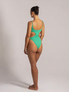 Side-back angle of a green swimsuit with open sides and minimal coverage, featuring adjustable shoulder straps.