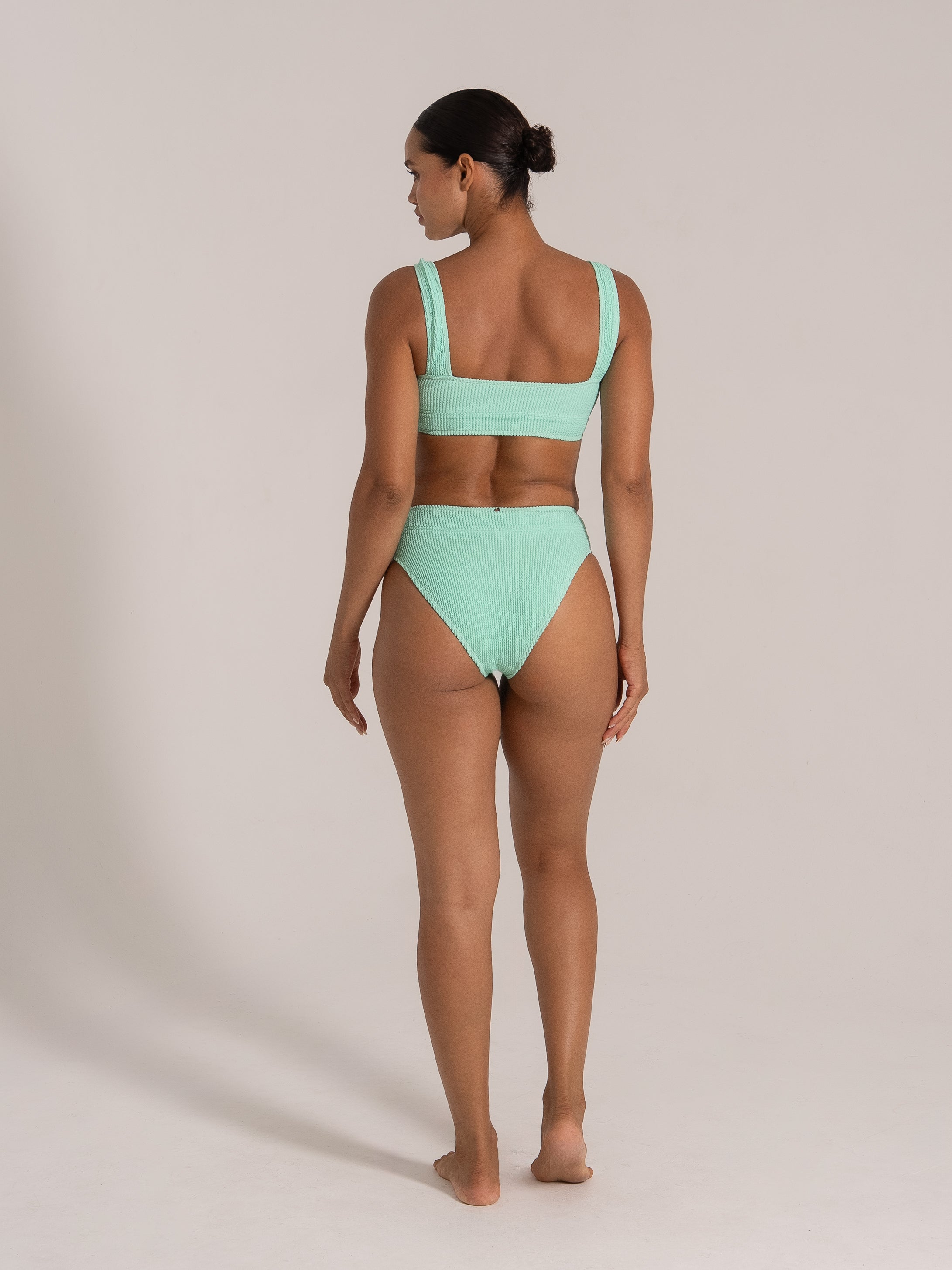 Back view of a mint green textured bikini set with wide straps and high waist bottom.