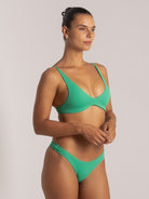 Side angle of soft green triangle bikini top featuring scoop neckline and stretch fit