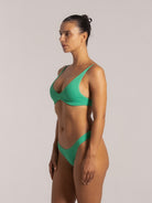 Side profile of woman in green bikini set with scoop V neckline and textured swim fabric